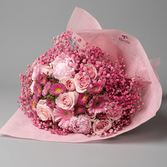 Bouquet of pink flowers wrapped in pink paper on a gray background